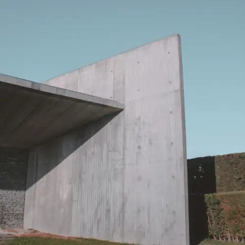 A building with a large concrete wall and grass.